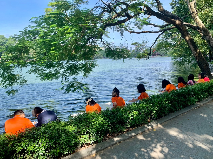 A group of people sitting on a bench by a body of water

Description automatically generated