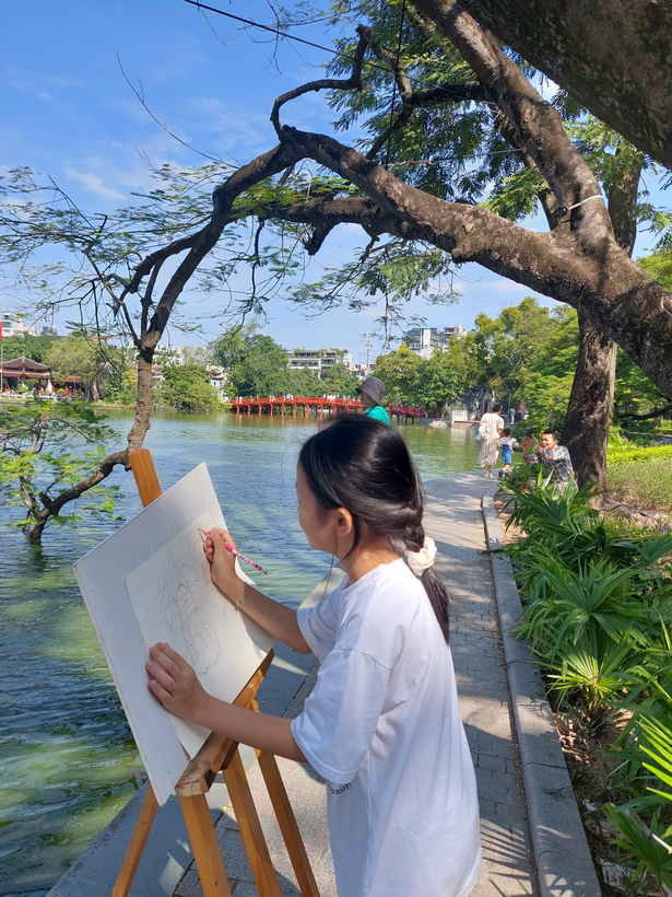 A person painting on a wooden easel

Description automatically generated