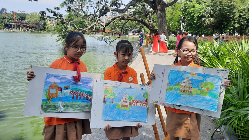 A group of young girls holding up paintings

Description automatically generated