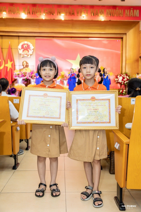 Two girls holding certificates in a classroom

Description automatically generated