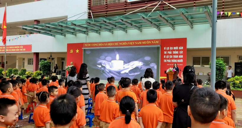 A group of children in orange shirts standing in front of a screen

Description automatically generated