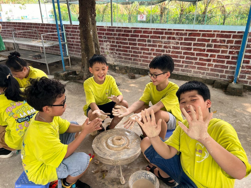 A group of boys in yellow shirts sitting on a stone table

Description automatically generated